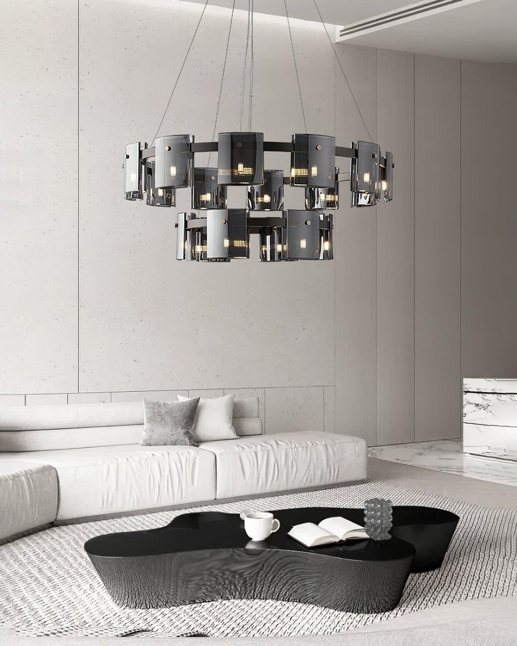 Two-tier black chandelier from Clérachic with smoked glass shades hanging above a black coffee table in a white lounge.