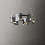 Lit black-frame chandelier from Clérachic with a smaller ring of smoked glass shades, against a dark grey wall.