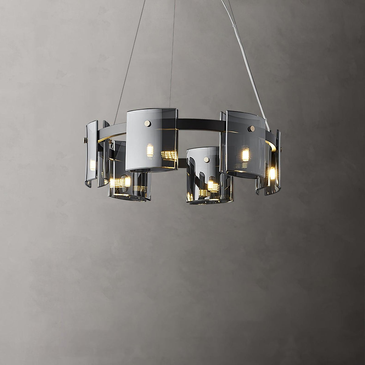 Lit black-frame chandelier from Clérachic with a smaller ring of smoked glass shades, against a dark grey wall.