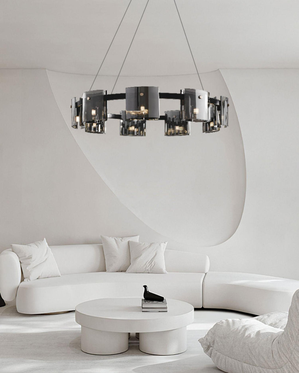 Black-frame Clérachic chandelier hung above a curved white sofa and a round white coffee table in a minimalist room.