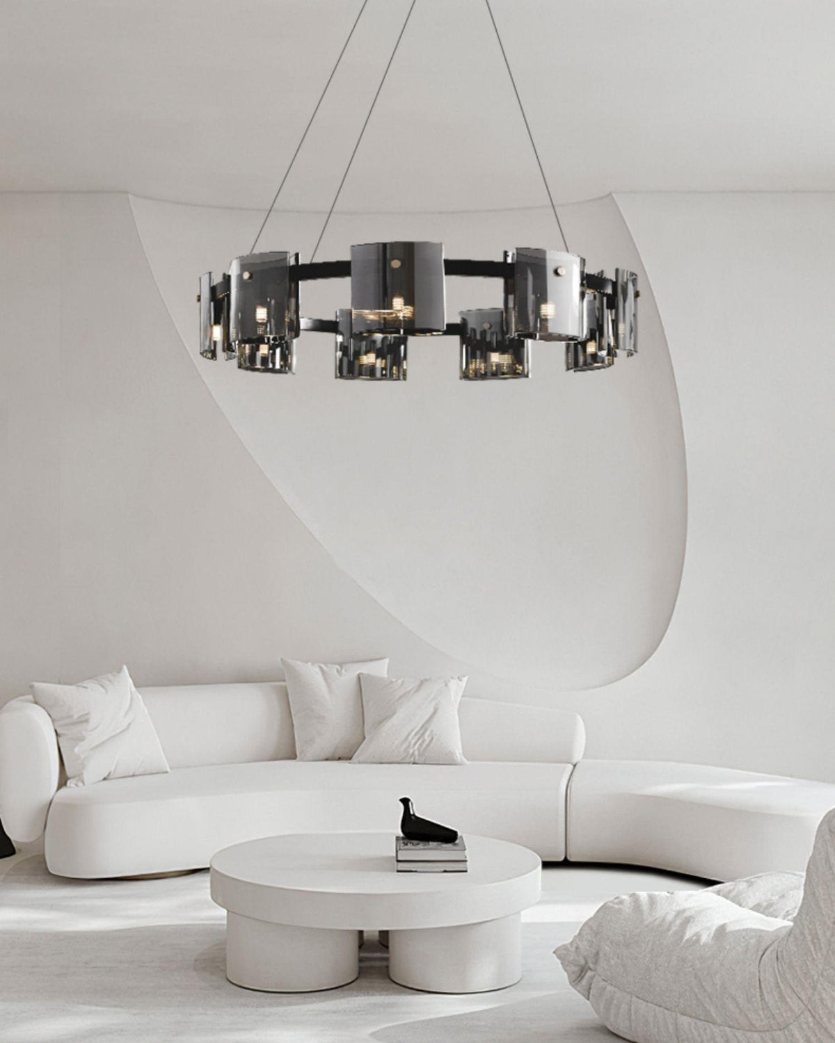 Black-frame Clérachic chandelier hung above a curved white sofa and a round white coffee table in a minimalist room.