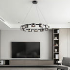 Black ring chandelier from Clérachic hung in a living room with a wall television, built-in shelves and a recessed ceiling.