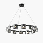 Wide black ring chandelier from Clérachic with smoked glass cylinders and three hanging cables, on a pale backdrop.