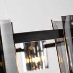 Angled close view of a black metal band on this Clérachic chandelier, with smoked glass panels and a lit bulb below.