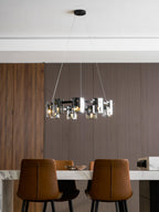 Lit black-frame chandelier from Clérachic with smoked glass shades above a marble table and tan leather chairs.