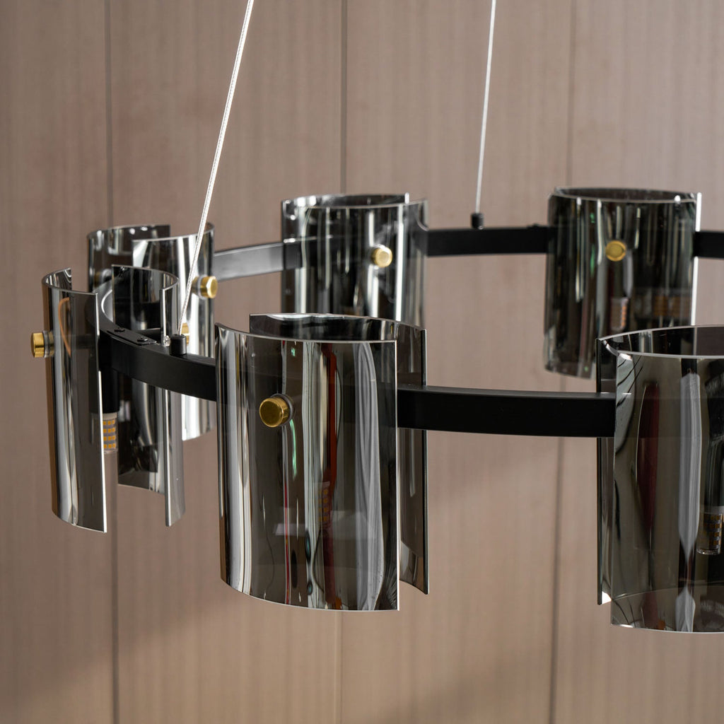 Close view of curved smoked glass shades and brass-coloured pins on this Clérachic chandelier, against a wood-toned wall.