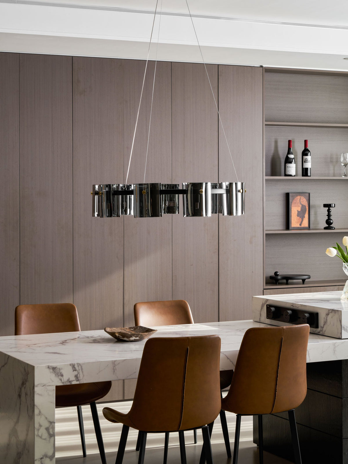 Unlit black chandelier from Clérachic seen almost edge-on above a marble table and leather dining chairs.