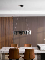 Black ring chandelier from Clérachic with smoked glass shades above a dining area, seen from a distance below a white ceiling.