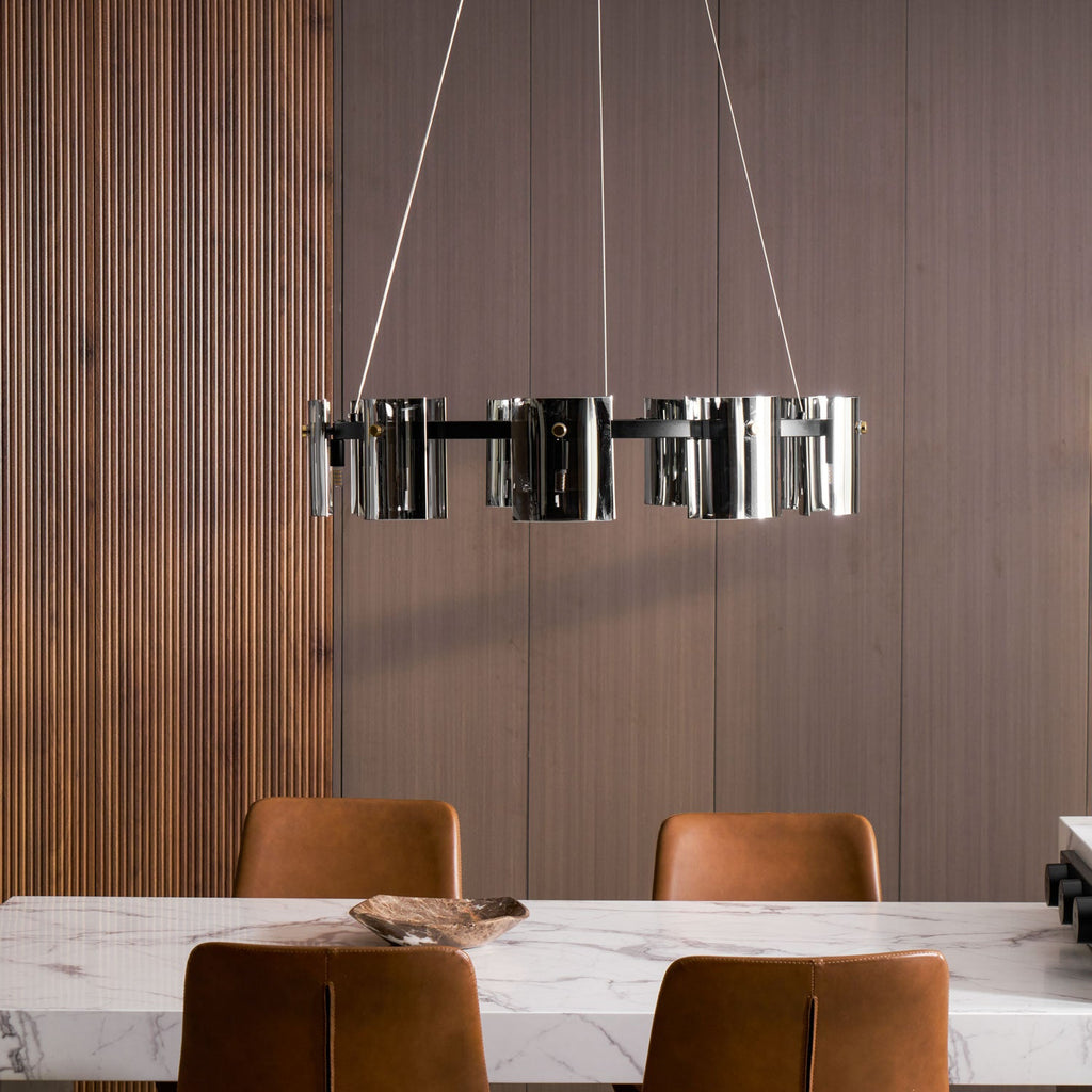 Smoked glass chandelier from Clérachic hung against a ribbed wood wall, with a marble table and leather chairs below.