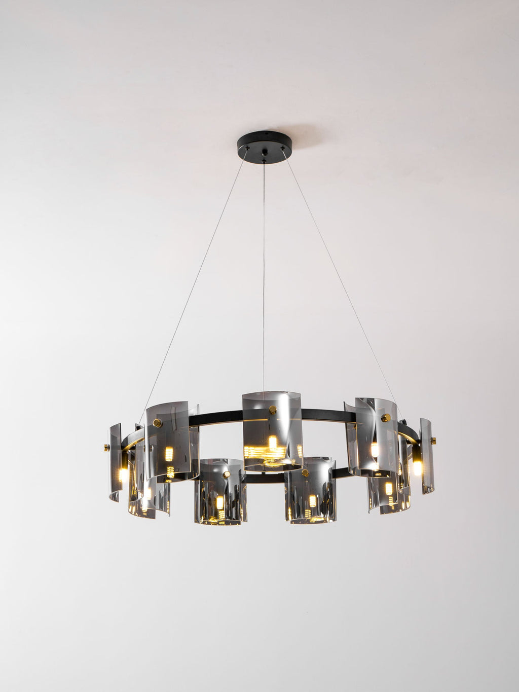 Black-frame chandelier from Clérachic with smoked glass shades and a round black canopy, lit, against a light backdrop.