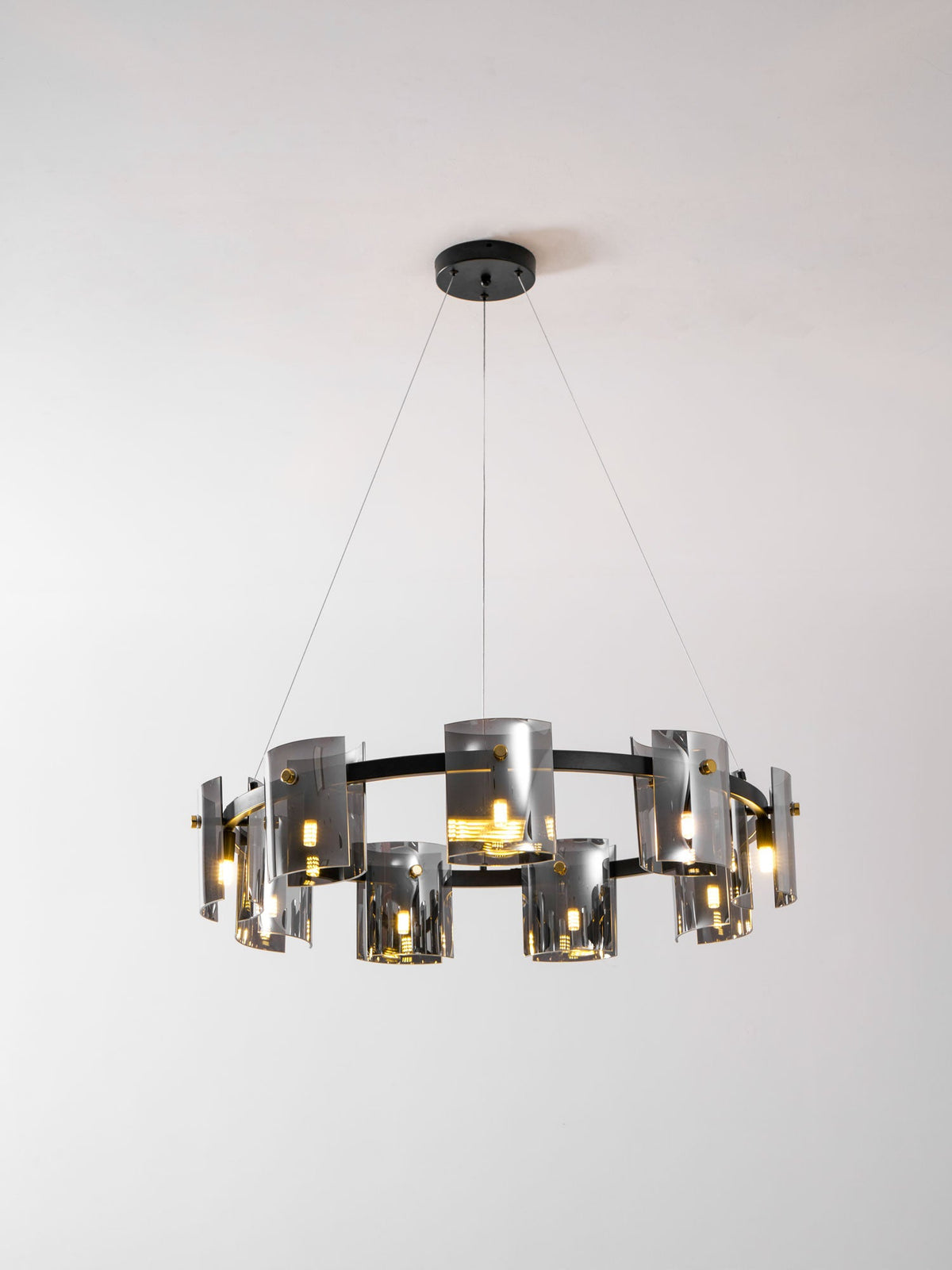 Black-frame chandelier from Clérachic with smoked glass shades and a round black canopy, lit, against a light backdrop.