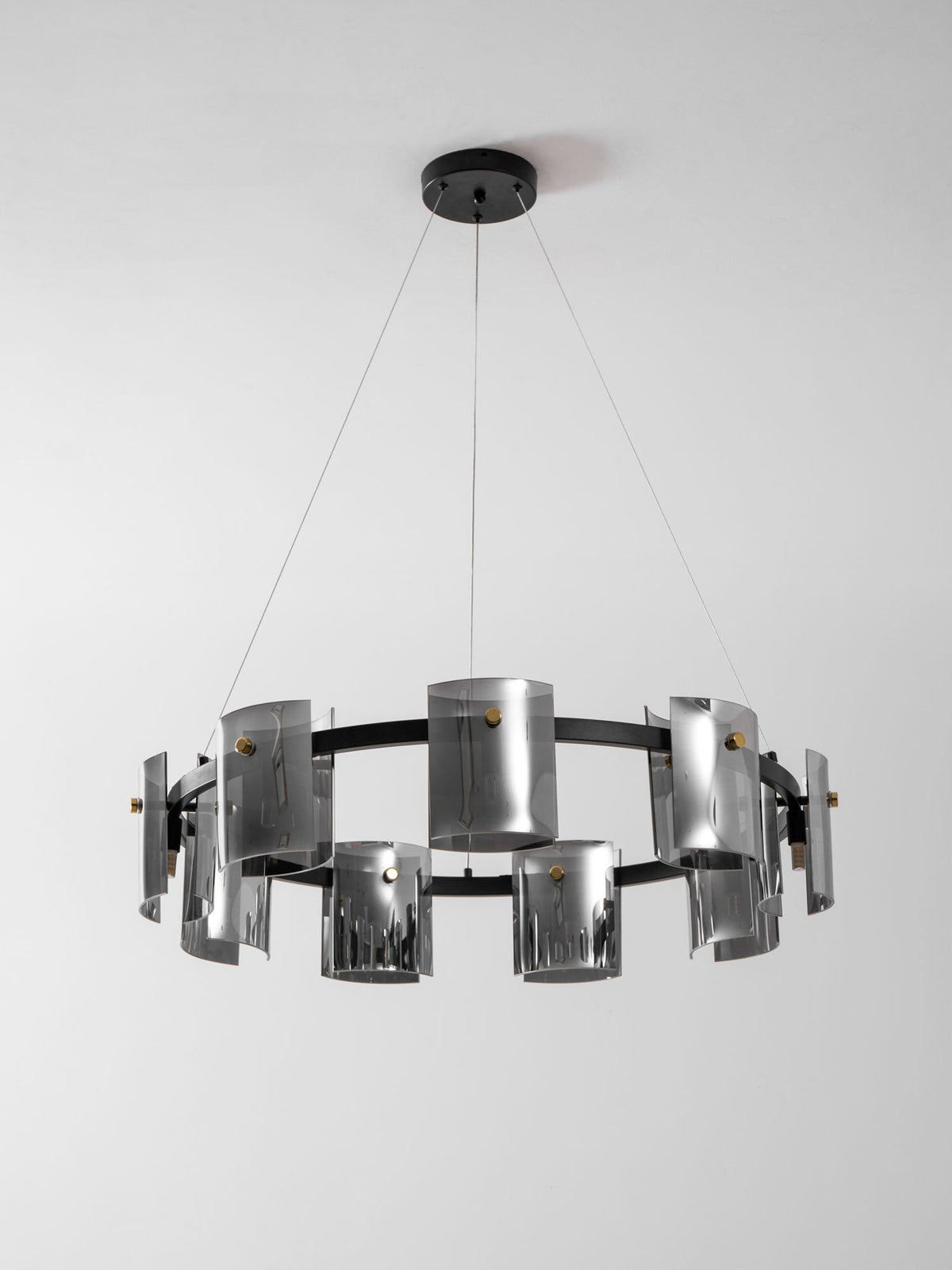 Black ring chandelier from Clérachic with smoked glass shades staggered around the band, below a round black canopy.