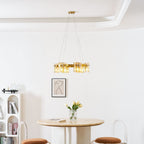 Gold-frame chandelier from Clérachic hung in a white room with a cornice, a round table and arched shelves in the background.