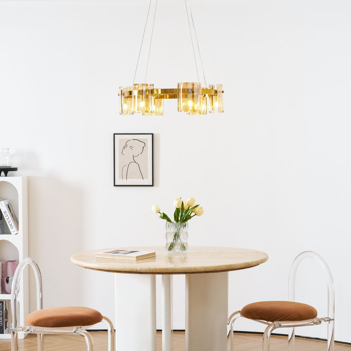 Gold-frame Clérachic chandelier with amber shades above a framed portrait, a vase of tulips and a round table with brown stools.