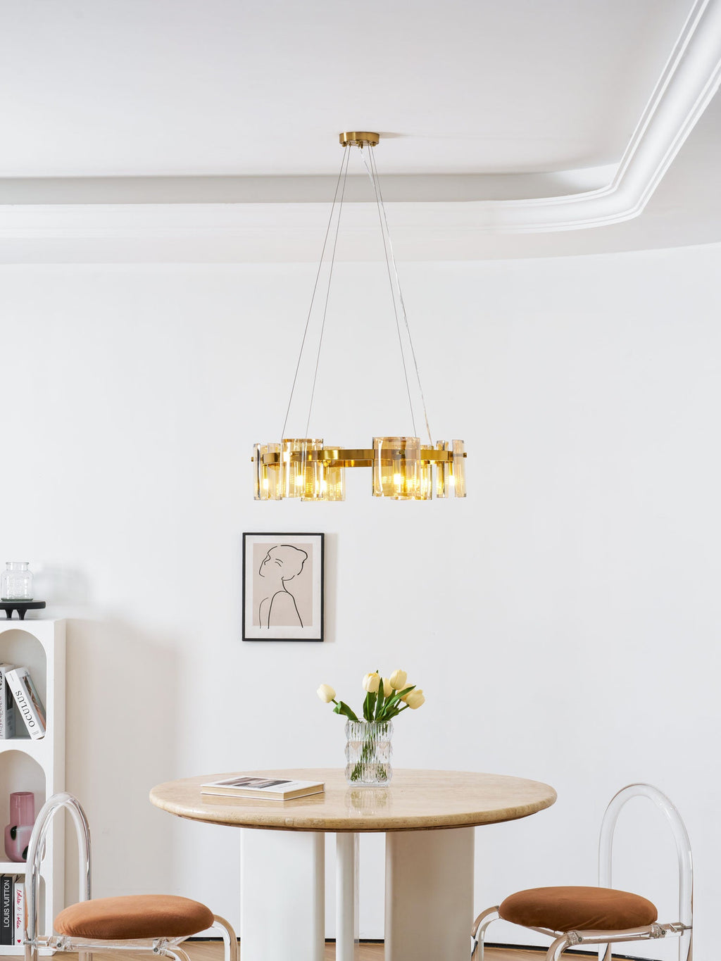 Gold ring chandelier from Clérachic below a white moulded ceiling, with a framed portrait and a round table with tulips beneath.