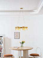 Gold ring chandelier from Clérachic below a white moulded ceiling, with a framed portrait and a round table with tulips beneath.