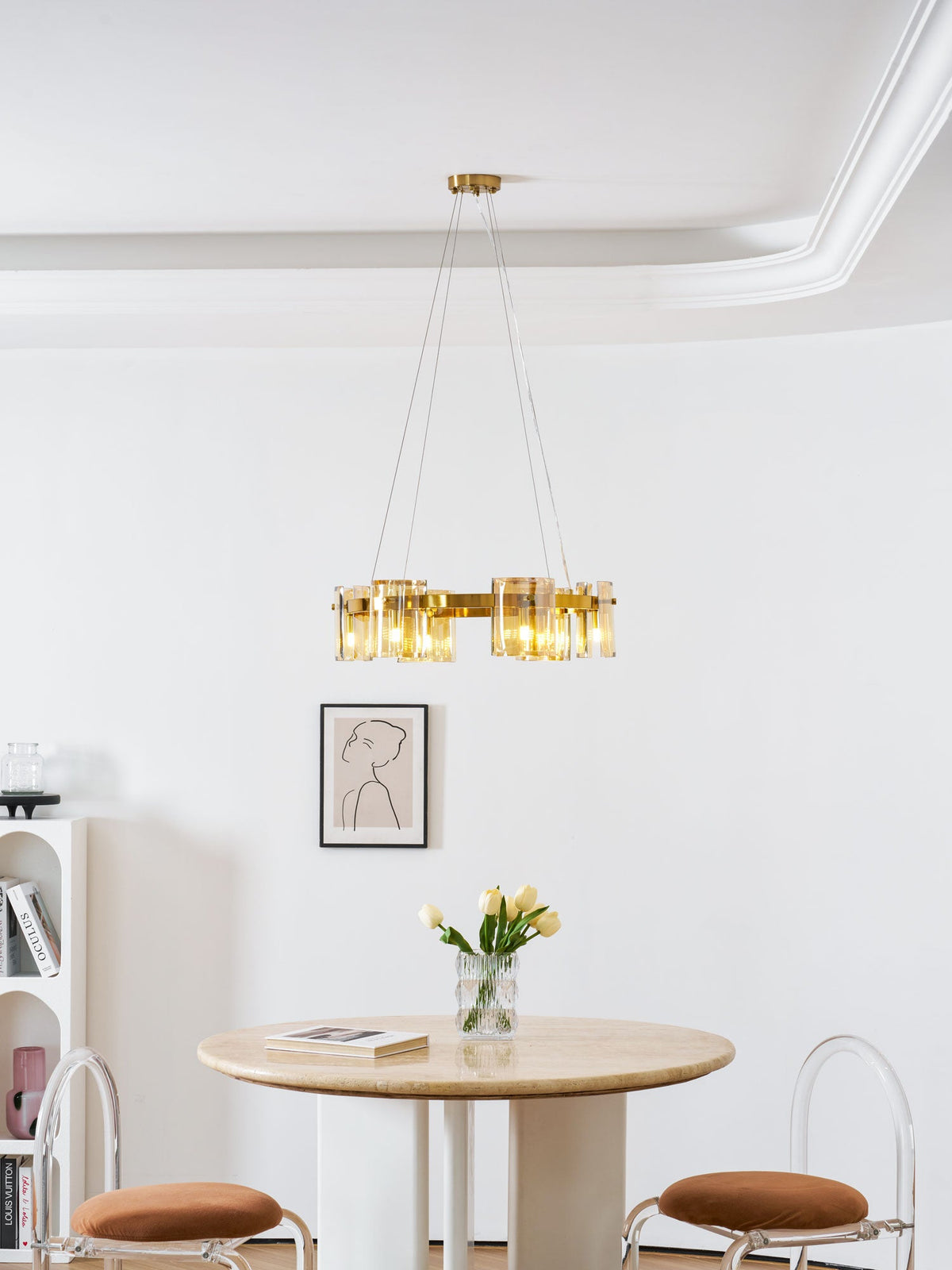 Gold ring chandelier from Clérachic below a white moulded ceiling, with a framed portrait and a round table with tulips beneath.
