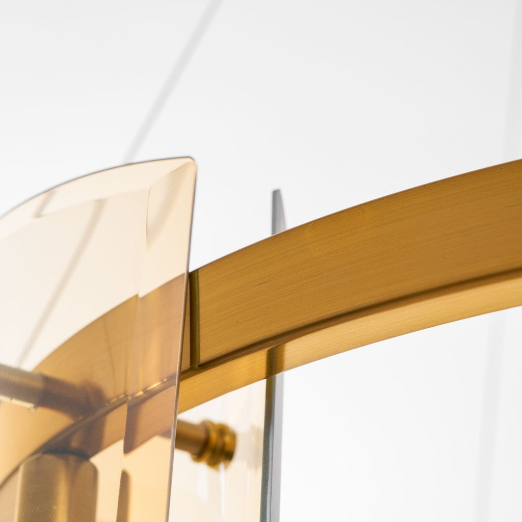 Close view of the brushed gold band and an amber glass panel on this Clérachic chandelier, with a brass-coloured fixing pin.