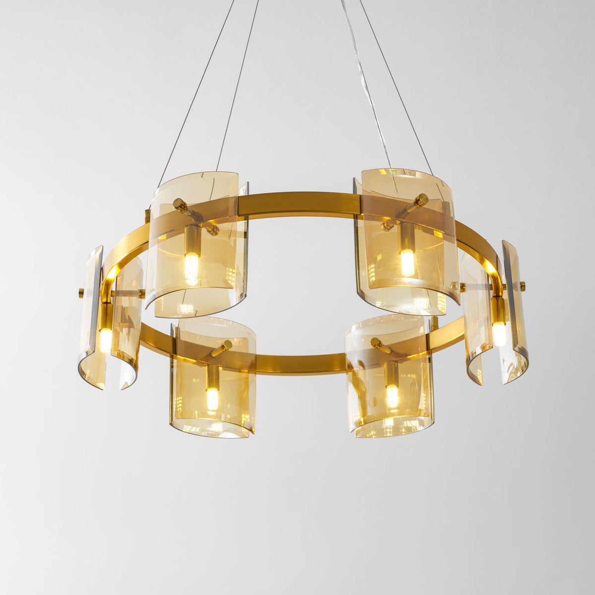 Gold-frame ring chandelier from Clérachic seen from below, with six amber glass shades lit and hung on thin cables.