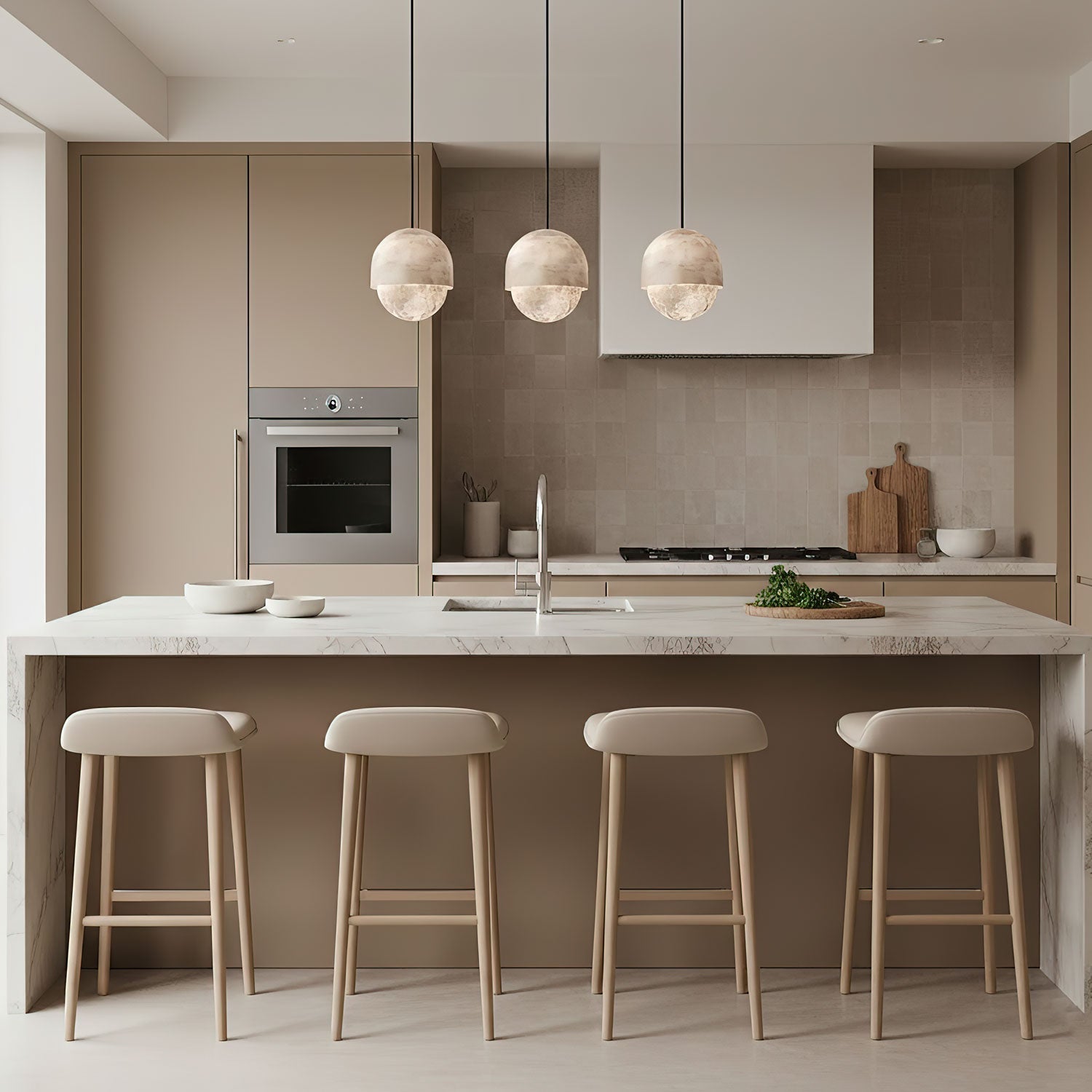 Three Clérachic Lunar pendants in a row above a pale kitchen island with oak stools.