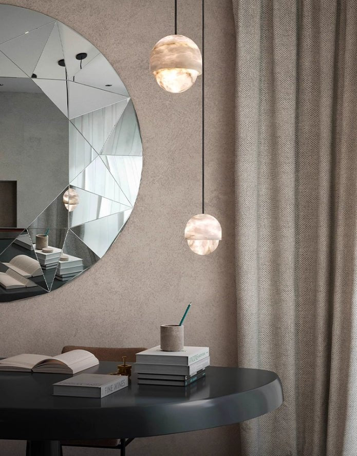 Clérachic Lunar pendants beside a round faceted mirror above a black desk.