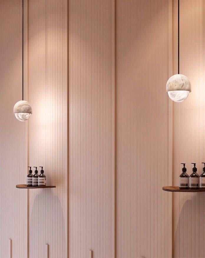 Two Clérachic Lunar pendants against a fluted pink wall above a narrow shelf.