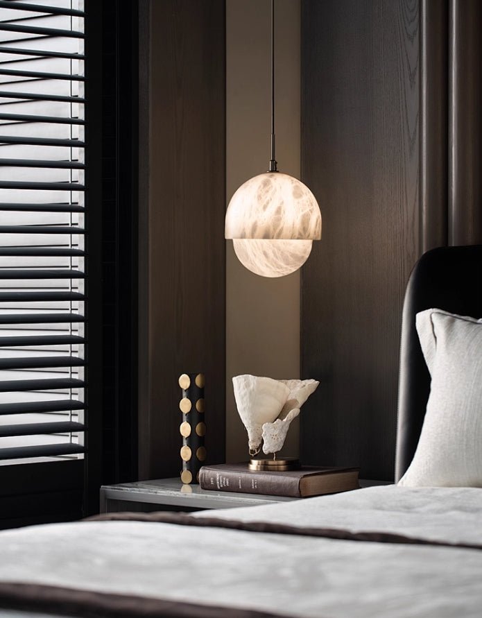 The Clérachic Lunar pendant lit in a dark bedroom beside timber blinds and a black headboard.