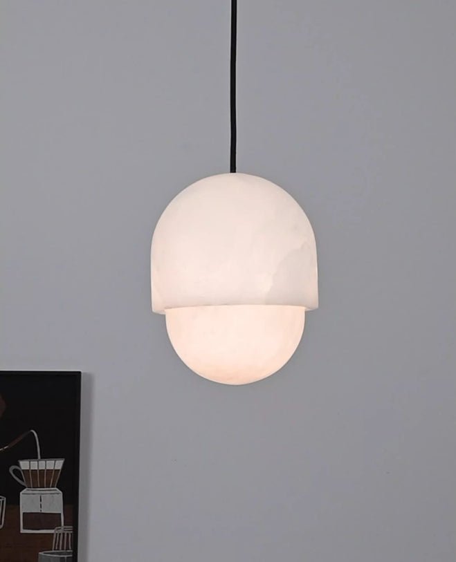 Clérachic Lunar pendant lit on grey, warm light escaping the gap beneath the stone cap.