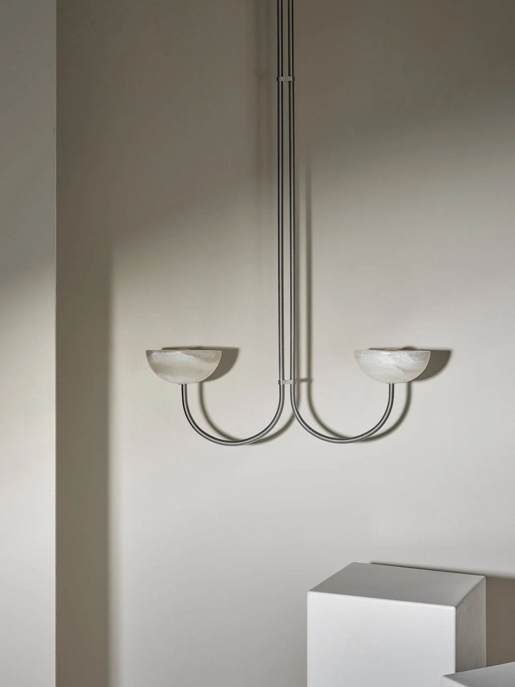 Clérachic Lunaris pendant in a satin metal finish, both bowls unlit against plaster.