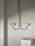 Clérachic Lunaris pendant in a satin metal finish, both bowls unlit against plaster.