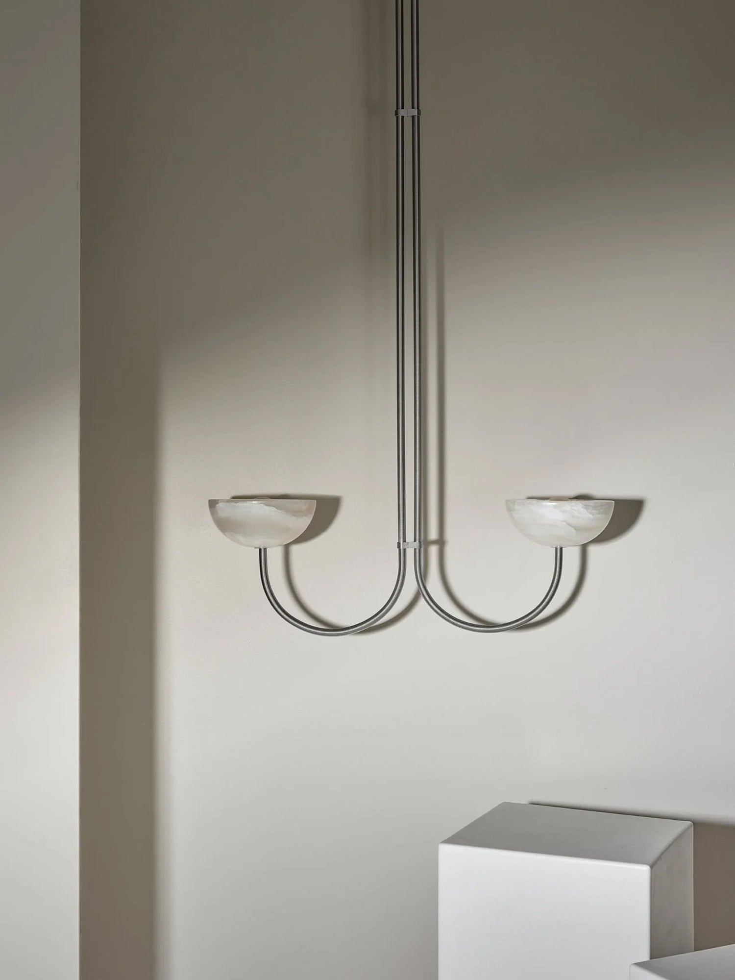 Clérachic Lunaris pendant in a satin metal finish, both bowls unlit against plaster.