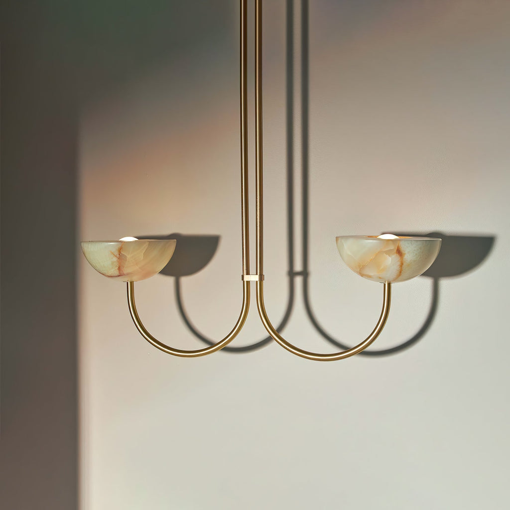 Clérachic Lunaris pendant in brass with two alabaster bowls lit above a pale wall.