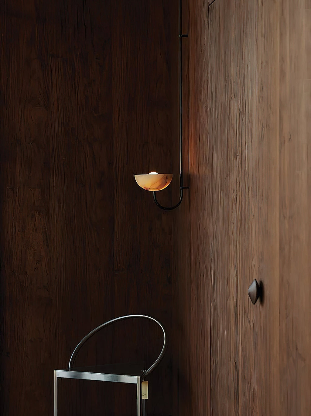 Clérachic Lunaris single-arm light on a dark timber wall in a dim, quiet room.