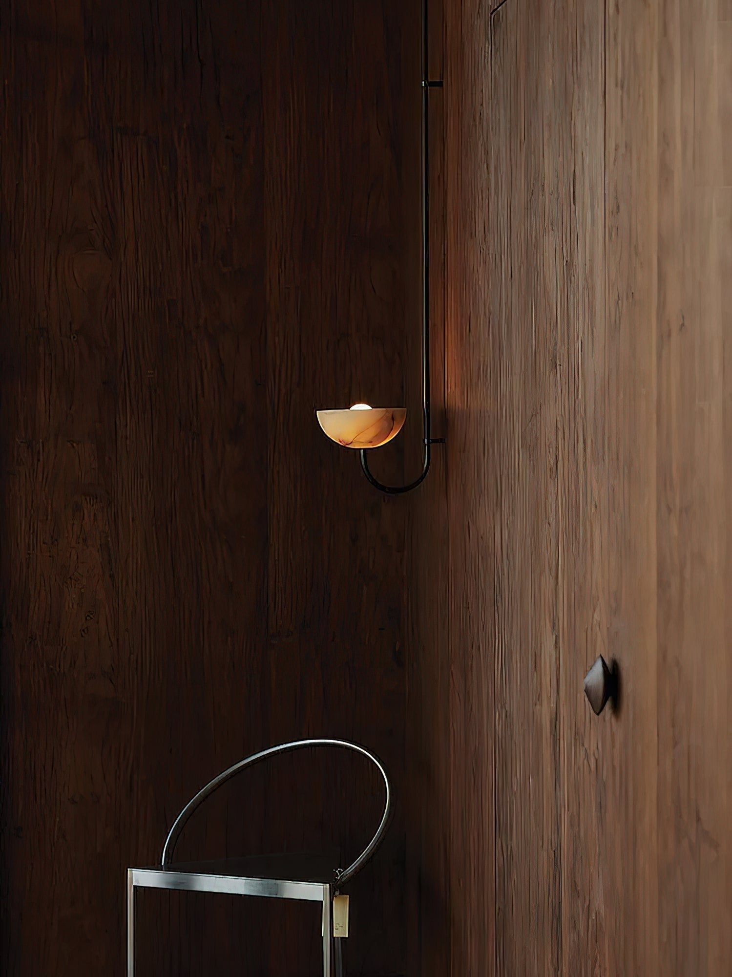 Clérachic Lunaris single-arm light on a dark timber wall in a dim, quiet room.