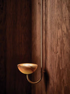 The Clérachic Lunaris bowl in brass on walnut panelling, amber veining across the stone.