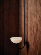 The Clérachic Lunaris single light in black finish, alabaster bowl against dark wood.