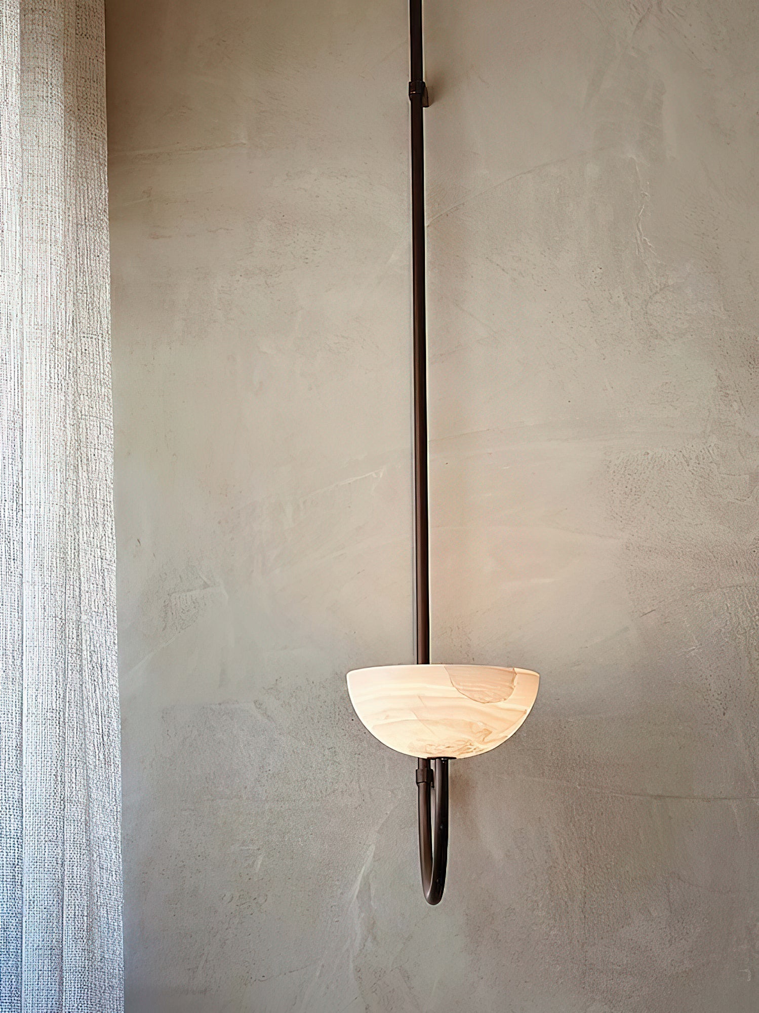 The Clérachic Lunaris single pendant on a plaster wall beside a sheer linen curtain.