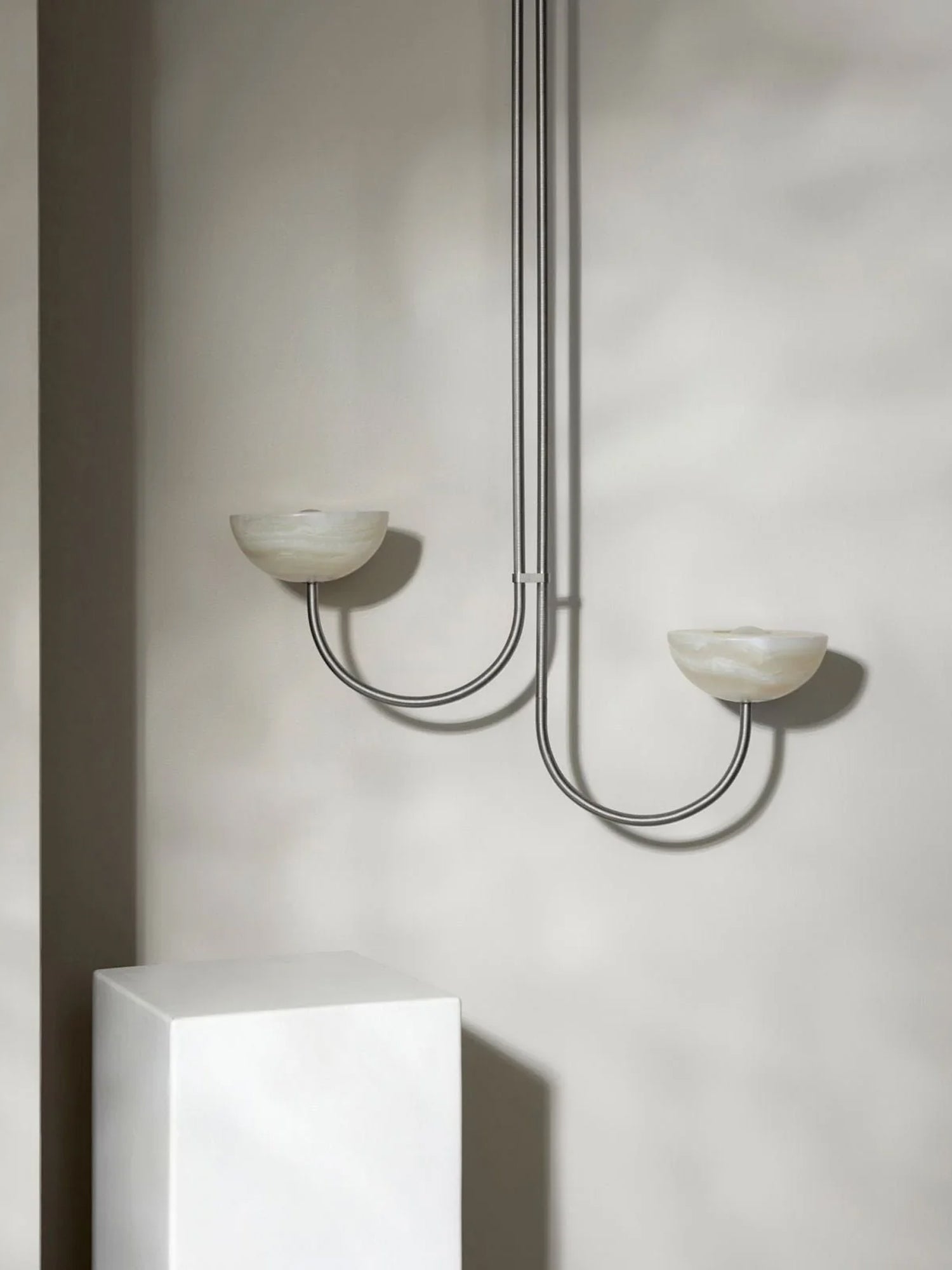 Clérachic Lunaris pendant in nickel, twin stone bowls throwing light up the wall.
