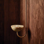 Clérachic Lunaris single light in brass on walnut, warm bowl glowing at eye level.