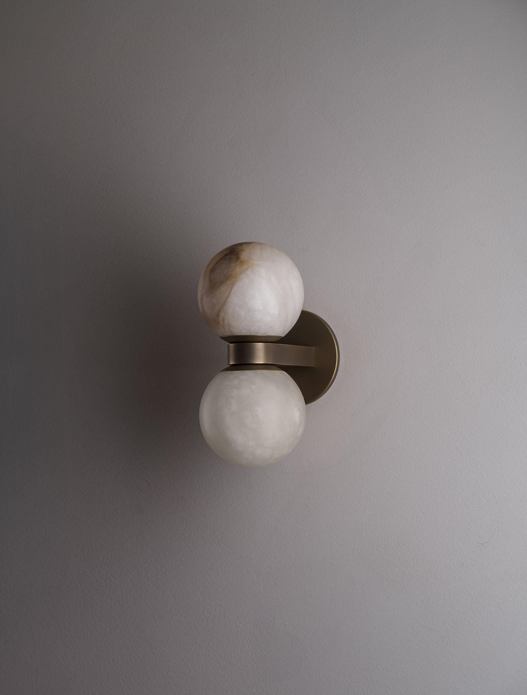 The Clérachic Lush Twin Globe Wall Sconce unlit on a pale plaster wall, its bronze arm and stacked alabaster globes reading as a quiet detail.