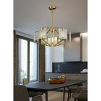 Clérachic chandelier above a dining table, brass frame catching daylight from the window alongside it.