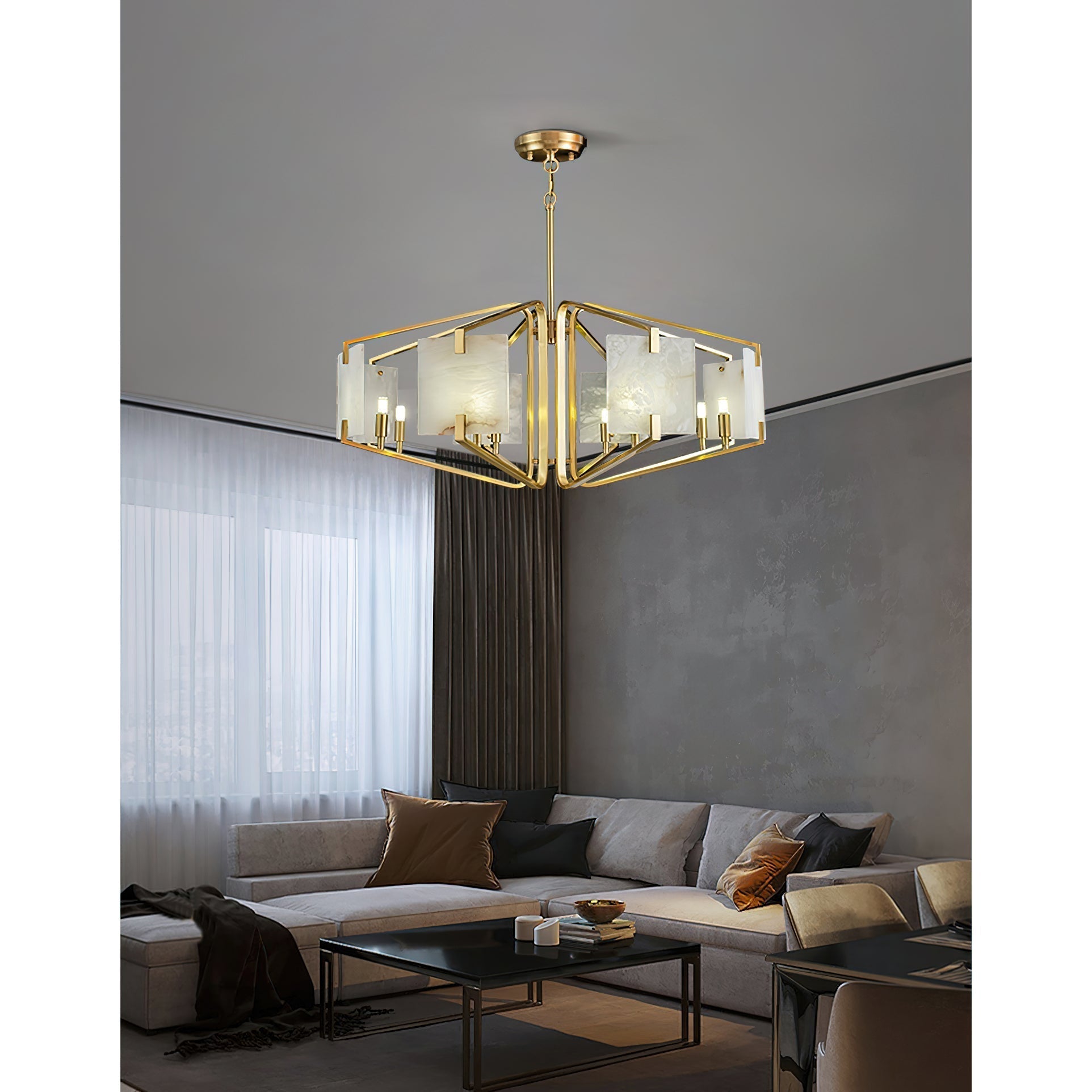 The Clérachic chandelier in a bright living room, brass arms and pale alabaster set off by sheer curtains.