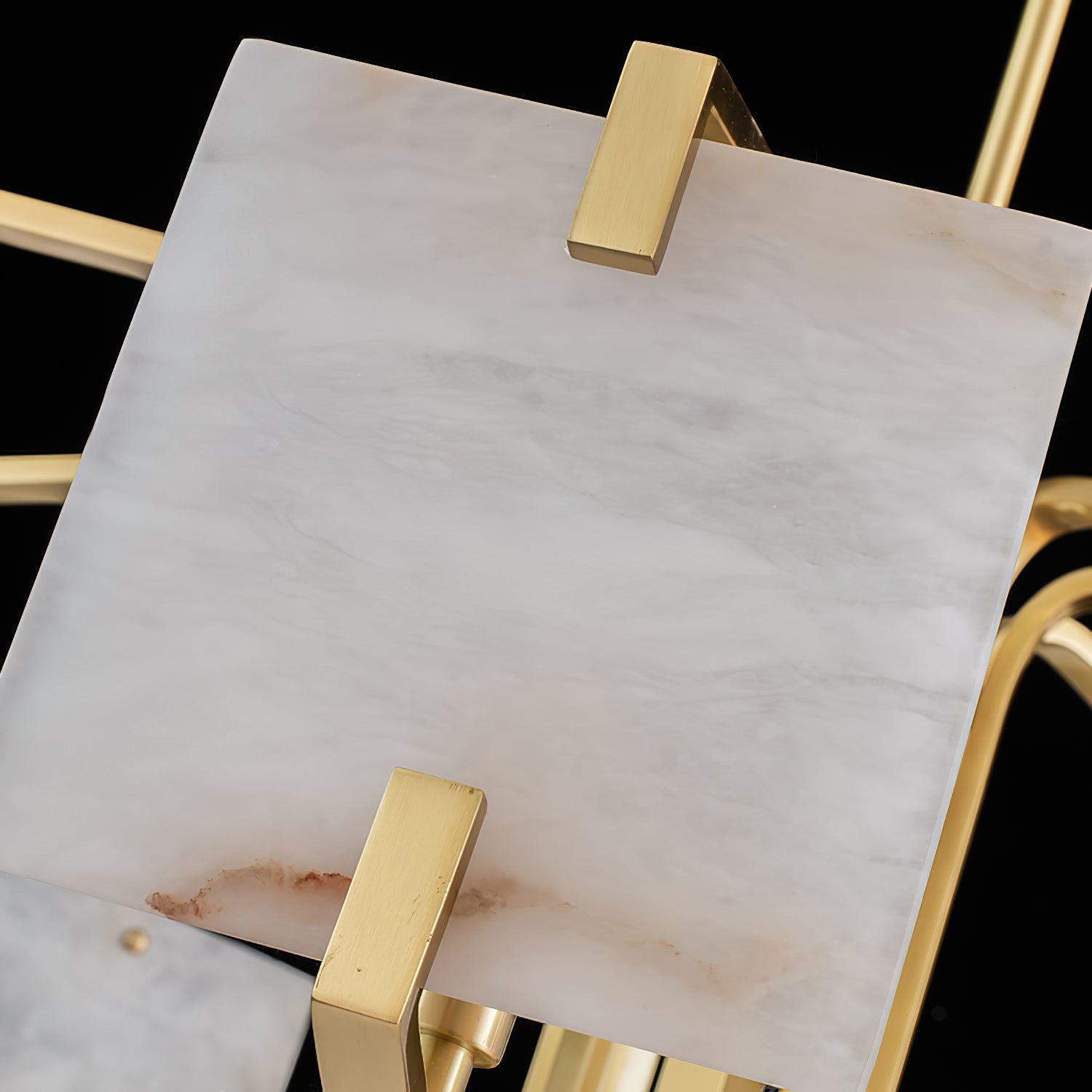 A single hand-carved alabaster panel on the Clérachic chandelier, held in brass clips with veining lit through.