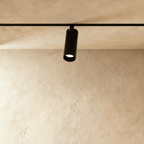 Clérachic track spotlight hanging clear of the ceiling on a short bracket that straddles the rail.