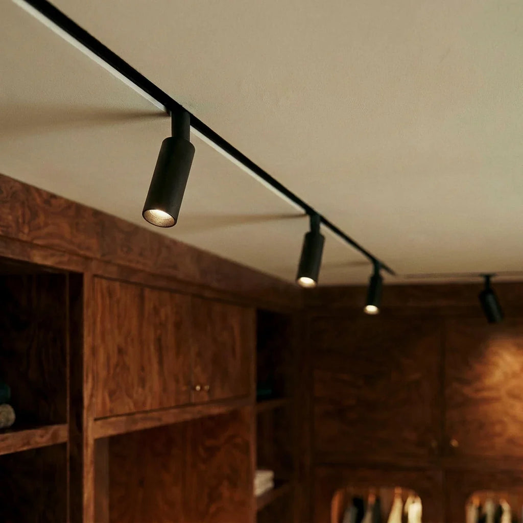 Clérachic track spotlights along one run, the heads aimed down over burl-wood cabinetry and open shelves.