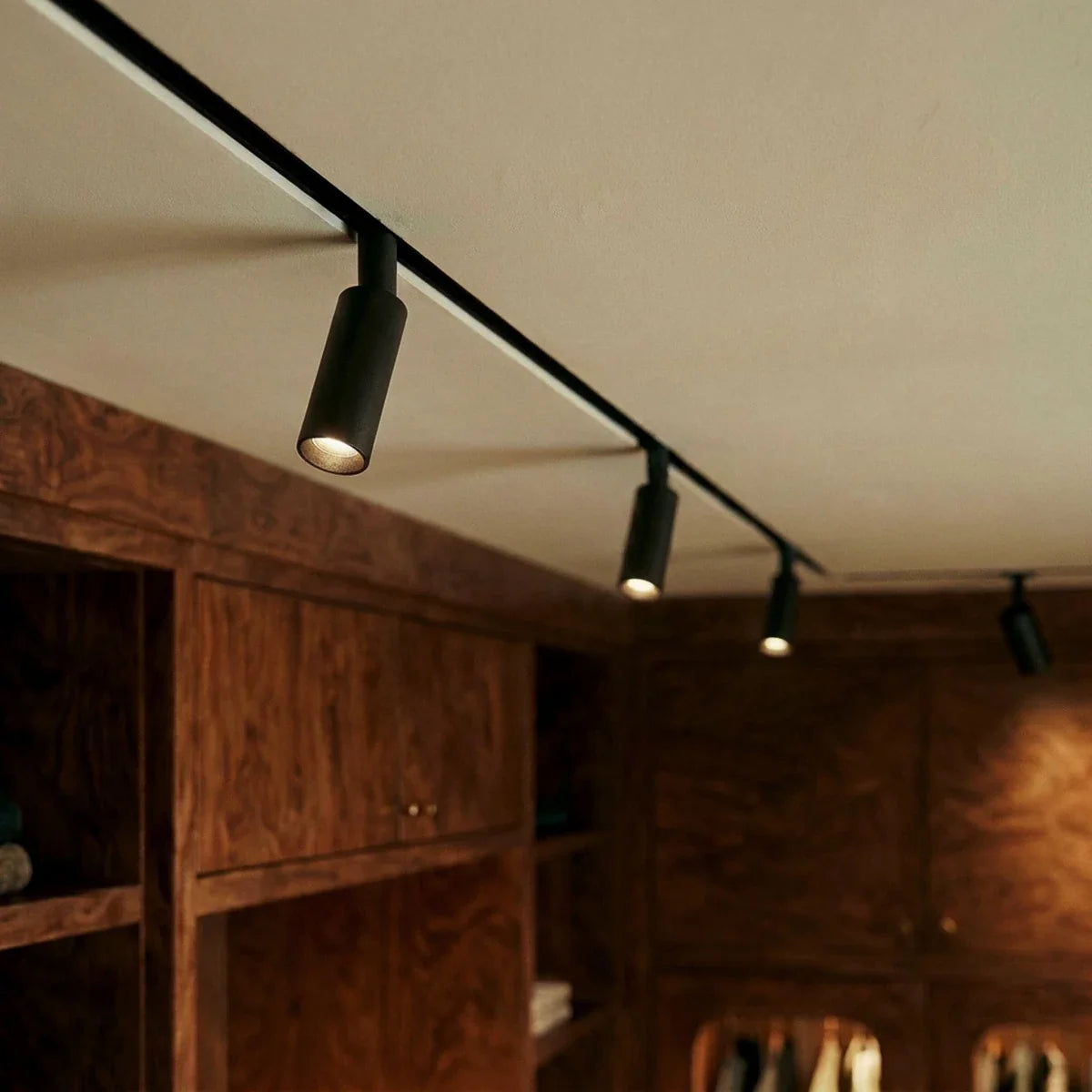 Clérachic track spotlights along one run, the heads aimed down over burl-wood cabinetry and open shelves.