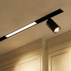 Clérachic track lighting below crown moulding, a lit recessed bar and one tilted spotlight on the same run.
