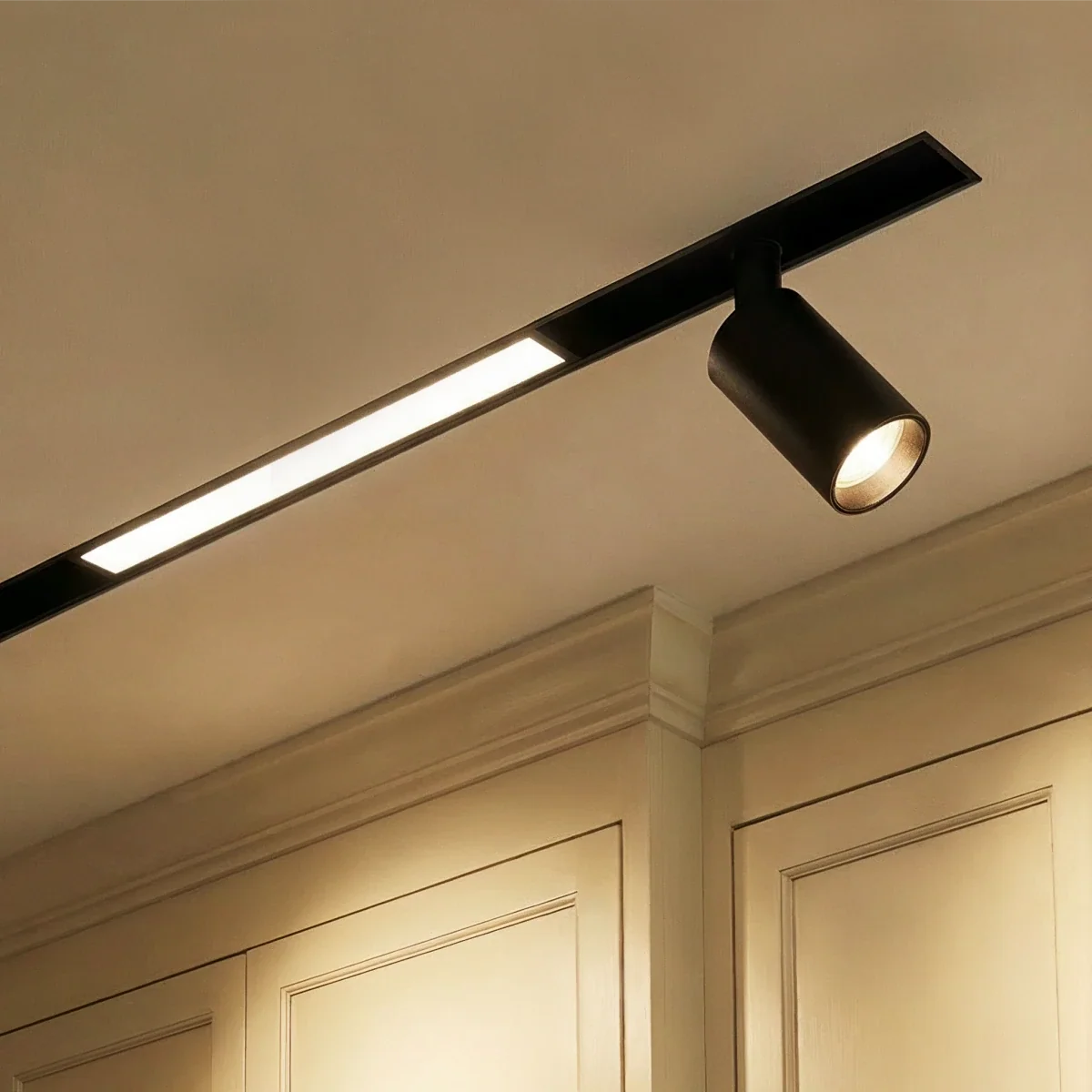 Clérachic track lighting below crown moulding, a lit recessed bar and one tilted spotlight on the same run.