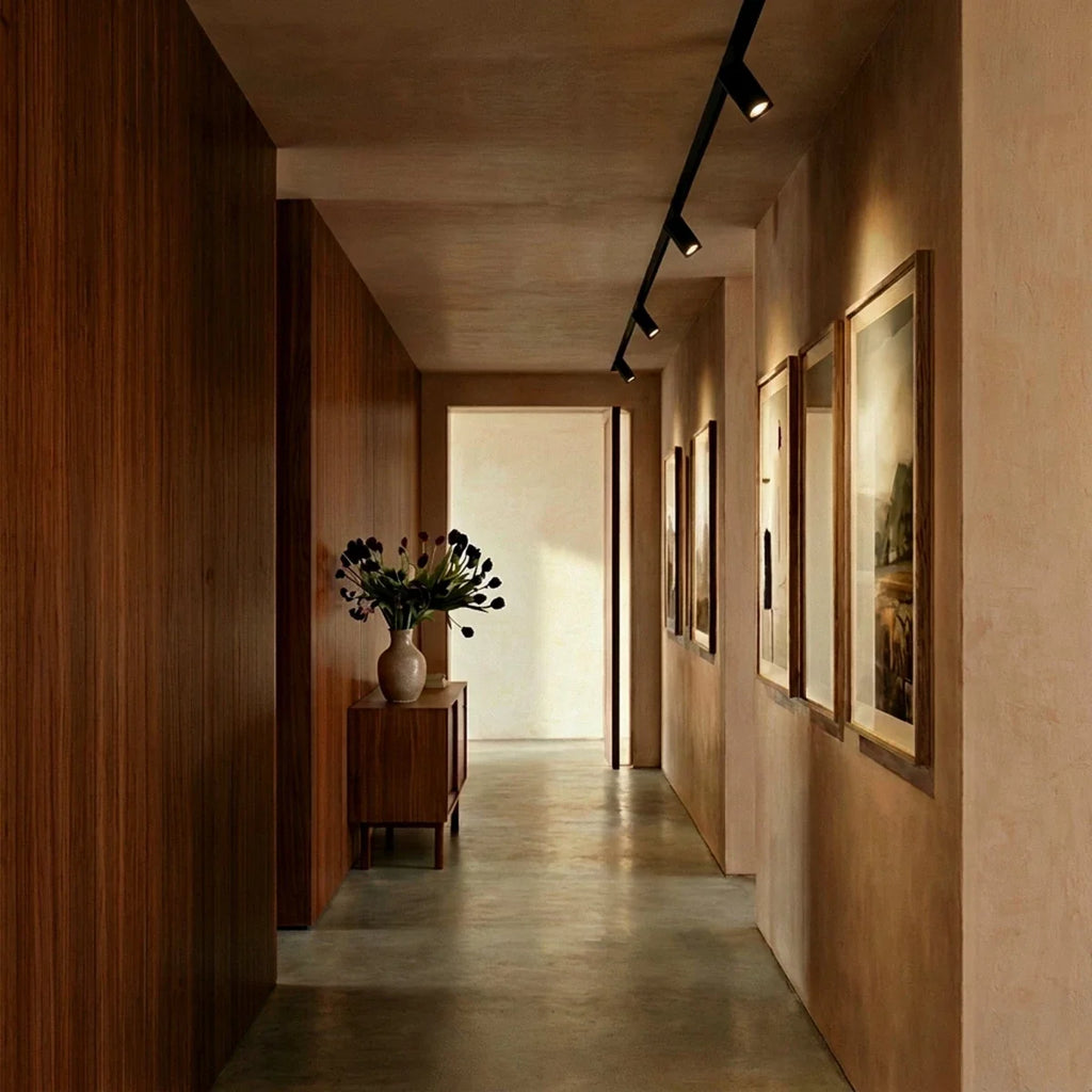 Clérachic track spotlights in a hallway, the run following the ceiling above a line of framed pictures.
