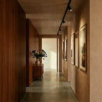 Clérachic track spotlights in a hallway, the run following the ceiling above a line of framed pictures.